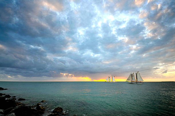 Sundown Schooners in Key West Beautiful, "postcard-quality" scene of schooners against the setting sun to the west taken from the beach jetty at Fort Zachery Taylor park in Key West, Florida, the beach/sunset corner in December. mike cherim stock pictures, royalty-free photos & images