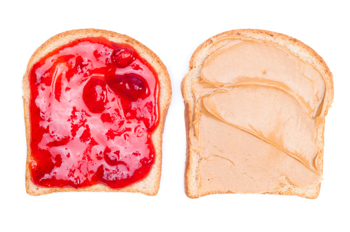 Two pieces of bread; one with peanut butter and the other with strawberry jelly.