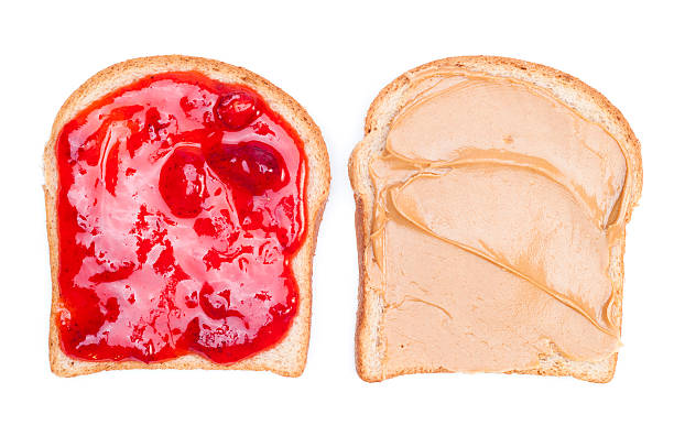 Close up of a peanut butter & jelly sandwich on white bread Two pieces of bread; one with peanut butter and the other with strawberry jelly. peanut butter and jelly sandwich stock pictures, royalty-free photos & images