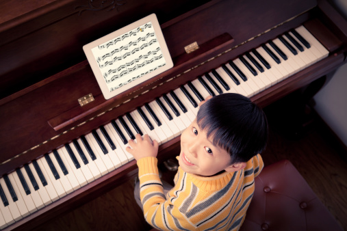 one asian Little boy learning to play the piano,Using Digital Tablet,
