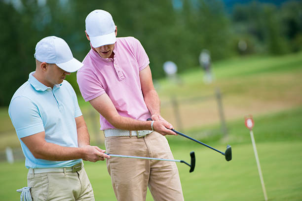 Golf Pro Teaching Male Golfer Golf pro teaching male golfer on putting green. golf concentration stock pictures, royalty-free photos & images