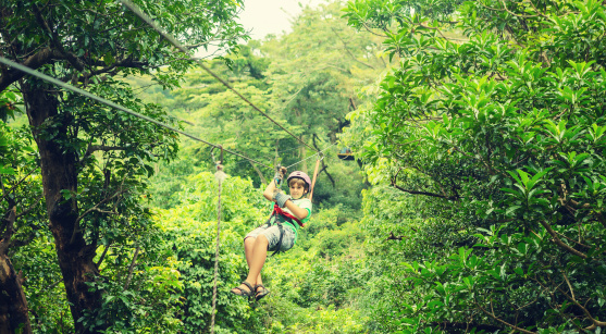 10 years old kid doing a Canopy Tour Costa Rica, zip lines between trees, view of a tree platform.
