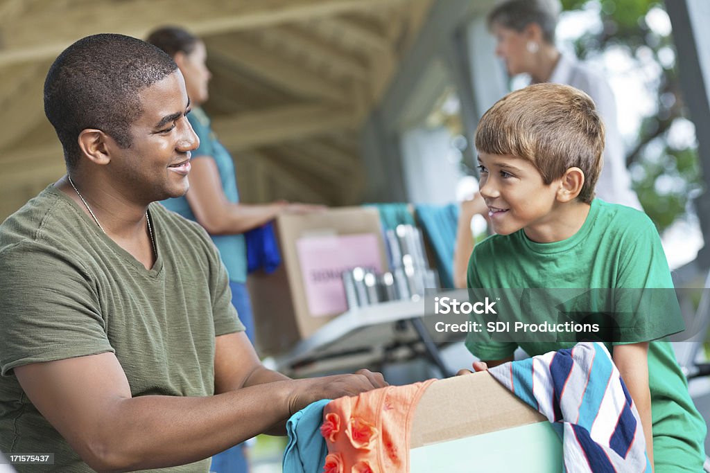 Человек с ребенком добровольческой деятельности в и питание, одежда, место для пожертвований - Стоковые фото Гаражная распродажа роялти-фри