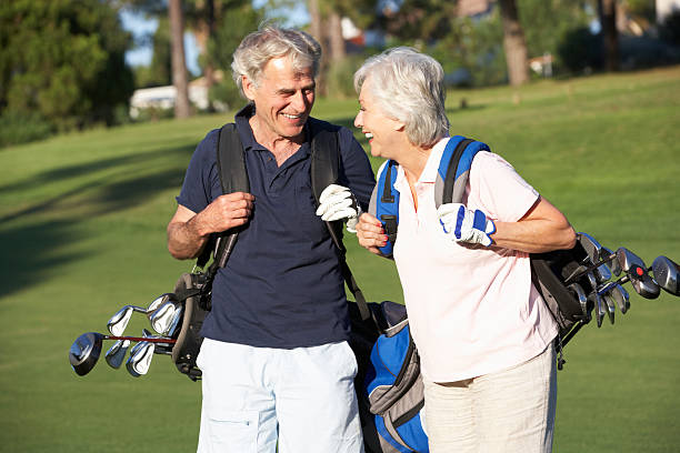 sênior casal desfruta de um jogo de golfe - senior couple golf retirement action - fotografias e filmes do acervo