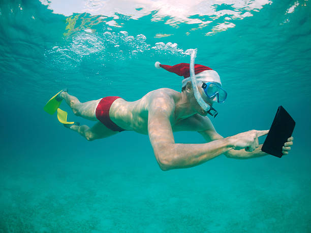 viaggio vacanze di natale santa cappello uomo snorkeling con digital tablet - men swimming trunks beach racing briefs foto e immagini stock