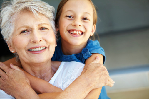 Closeup of a grandmother being embraced by her cute granddaughter - Copyspace