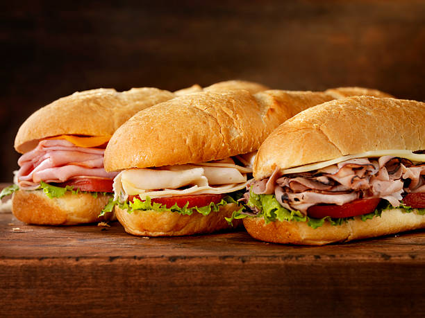 Three Foot Long Subs Three 12 inch  Submarine Sandwiches- Turkey, Ham and Cheese, Roast Beef and Swiss with Lettuce and Tomato on Crusty Buns - Photographed on Hasselblad H3D2-39mb Camera sandwich stock pictures, royalty-free photos & images