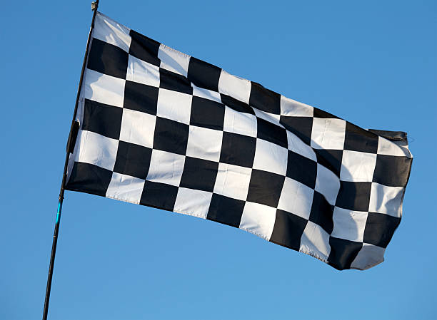 istock Black and white checkered flag flying against blue sky 171576113