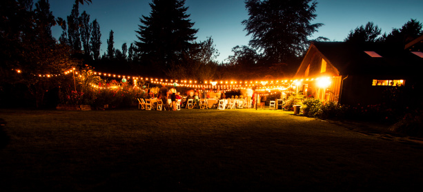Long exposure of an outdoor wedding ceremony at twilight and guests having a fun party. Motion blur makes any people unrecognizable.