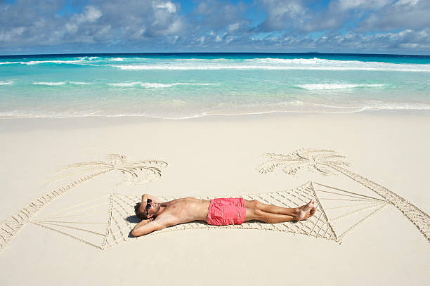 calções cor-de-rosa homem relaxa numa rede tropical praia de areia - hammock beach vacations tropical climate imagens e fotografias de stock