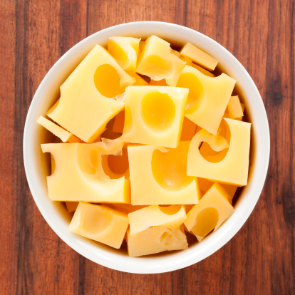 Top view of white bowl full of  gruyere cheese cubes