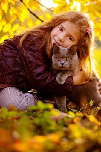 Outdoor Portrait of Little Girl Hugging Her Cat. Autumn