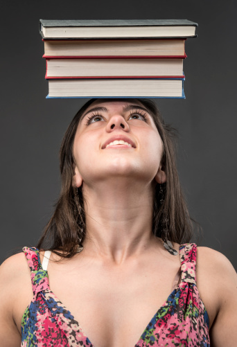 hispanic teenage girl with a stack of books on her head