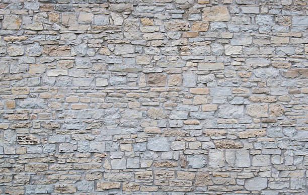 Wide shot of a plain limestone wall Background shot of an old limestone wall. stone wall stock pictures, royalty-free photos & images