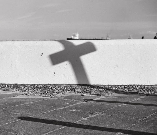 A road direction sign and its pole cast a cross-shaped shadow. The scene is Sunderland's seafront and a ship is visible in the background. Scan from Fujifilm Neopan 400