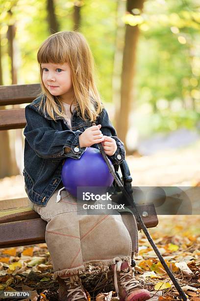 Kleines Mädchen Sitzen Auf Der Bank Im Park Stockfoto und mehr Bilder von Kind - Kind, Umherblicken, Blatt - Pflanzenbestandteile