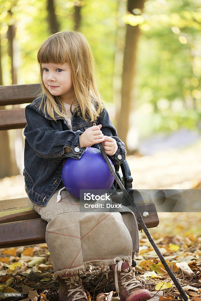 Маленькая девочка сидит на скамейке в парке, - Стоковые фото Ребёнок роялти-фри