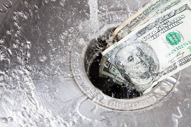 Money Down Drain Money being washed down garbade disposal loss stock pictures, royalty-free photos & images