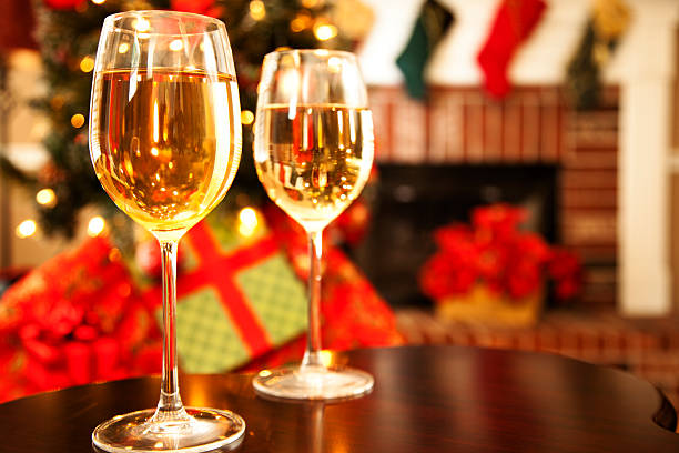 Two wine glasses on table with fireplace  and Christmas tree