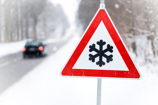 Traffic sign - Snow ahead, some snowflakes in the air, selective focus.