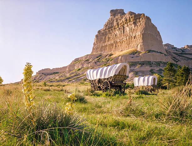 Conestoga covered wagons, Scotts Bluff National Monument, Oregon Trail, Nebraska Covered wagons in front of rocky bluff at Scotts Bluff National Monument in Nebraska.  This prominent bluff was an important landmark for those traveling on the Oregon Trail. covered wagon stock pictures, royalty-free photos & images