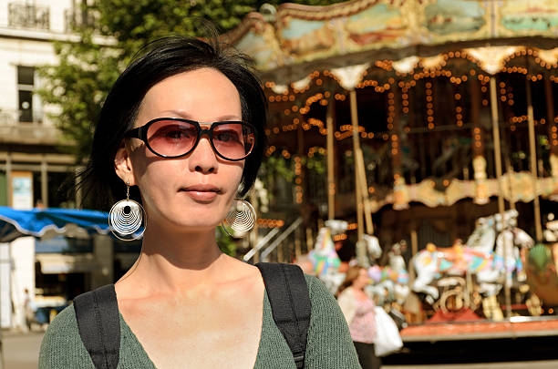Asian woman stand in front of carousel in Marseille, France.