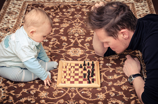 a fahther play chess with his baby son