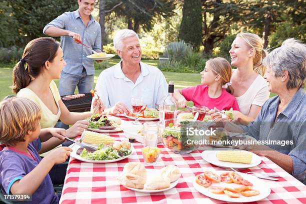 Three Generation Family Enjoying Barbeque In Garden Together Stock Photo - Download Image Now