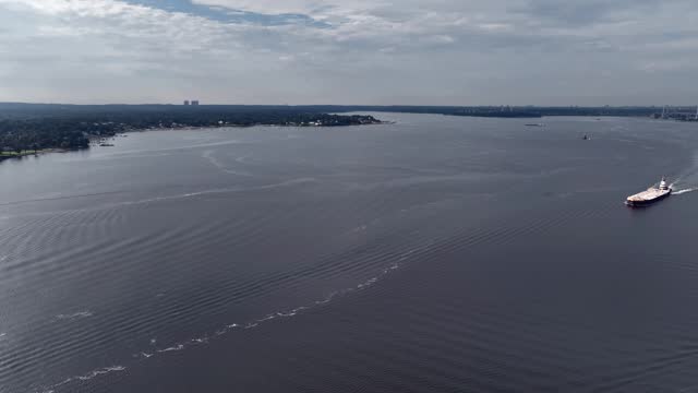 An aerial view of the tranquil Long Island Sound near Hart Island in New York on a cloudy day. The drone camera dolly in over the water towards boats and barges in motion.