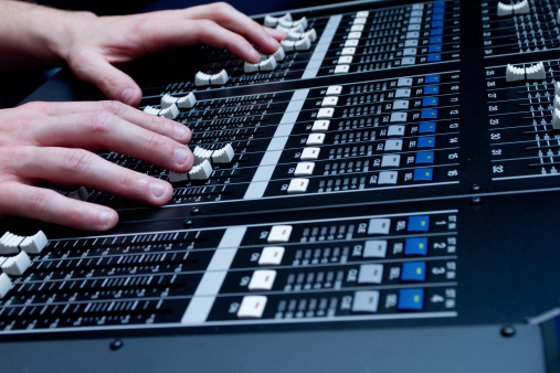 Dramatically lit detail of a new digital sound board, referred also to a console or desk.  This piece of high tech equipment is used in professional applications for live sound reinforcement and recording of music and spoken word.