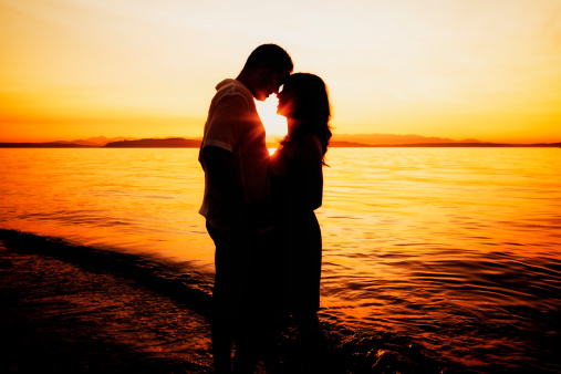 Silhouette of a young couple sharing a moment on a Seattle beach at sunset.