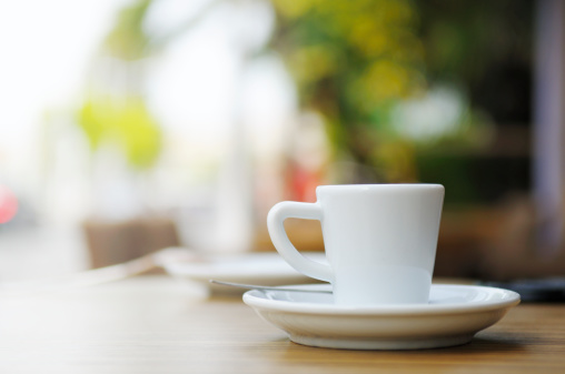 A fresh white cup of espresso coffee on a cafe table, outdoors. Taken in Cannes, France.