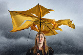 Beautiful unhappy blonde with ruined umbrella getting soaked in thunderstorm