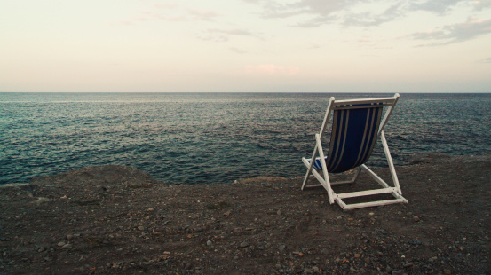 Stock Photo of a lonely sunchair on cliff line, Liguria - San Remo in 2010. Focus on beach chair. Soft image noise!
