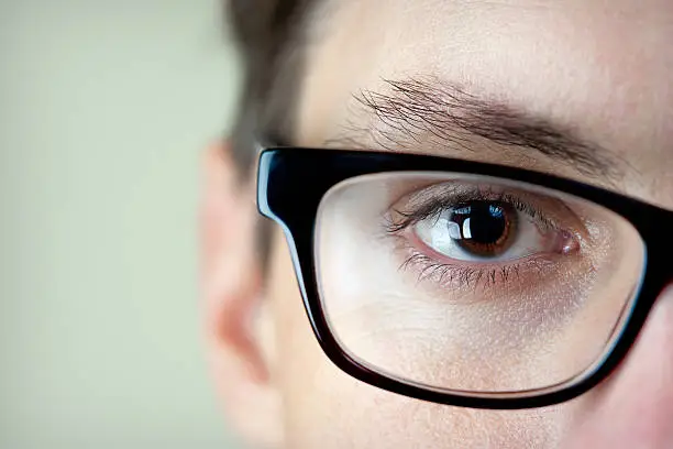 Close-up shot of a mans brown eye and glasses