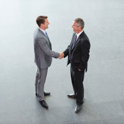 High angle view of businessmen shaking hands on floor.
