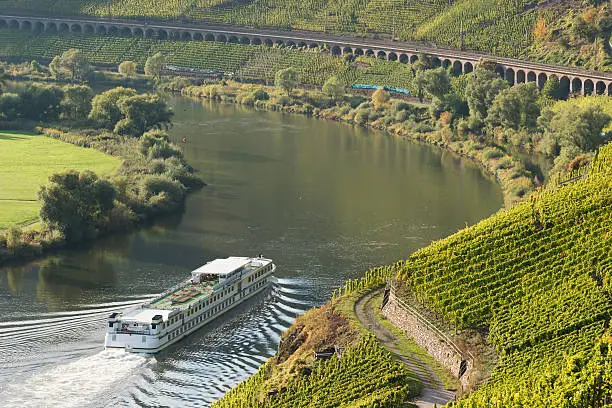 Ferry boat on Mosel river with railway slope viaduct Puenderich in background. The longest type in Germany.