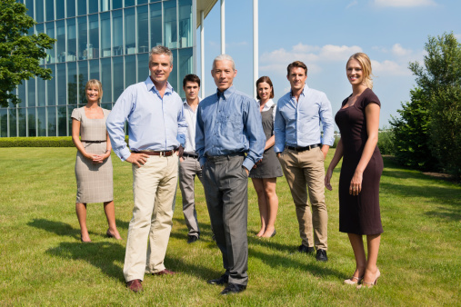 Full length portrait of confident business people standing at lawn.