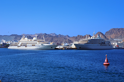 Wilayat Muttrah, Muscat, Oman: Al Said (left) and Fulk al Salamah (right), principal and secondary royal yachts, two of the 8 vessels of the Oman Royal Yacht Squadron, the Sultan's personal fleet of pleasure craft, operated by the Diwan of Royal Court Affairs. Mega yachts Moored at Port Sultan Qaboos (PSQ), Gulf of Oman / Arabian sea.