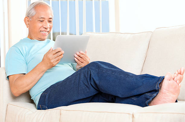 istock Mature Asian Man Relaxing on Couch with a Tablet 171580993