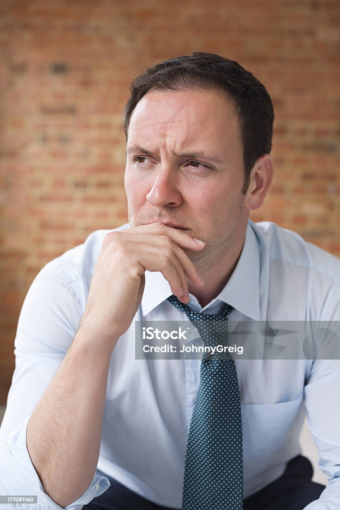 Contemplative Businessman Contemplative mid adult businessman looking away with hand on chin against brick wall. 30-39 Years Stock Photo