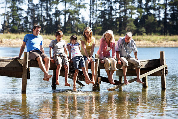 tres generaciones familia sentada en el embarcadero de madera - mother daughter grandmother jetty fotografías e imágenes de stock