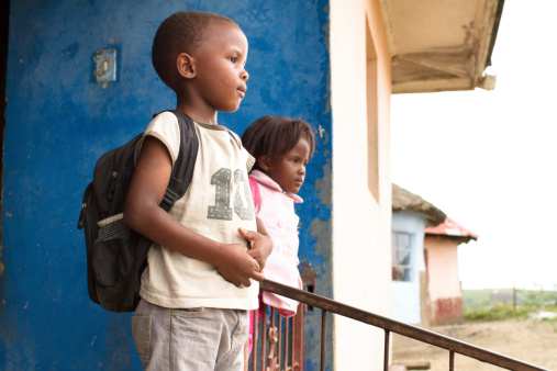 Portrait of two cute Xhosa children in rural South Africa hanging out on the porch of their house before heading to school.