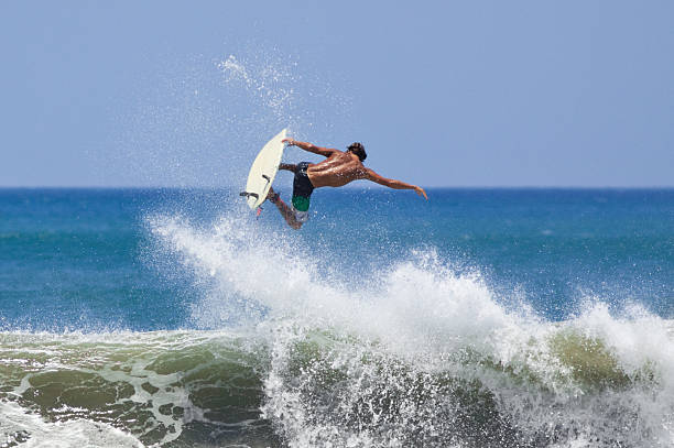 A man surfing and hitting big air above a wave stock photo