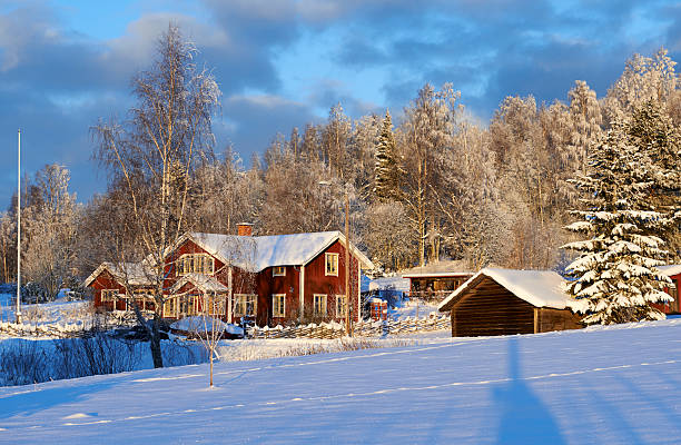 The tranquil beauty of a snowy Scandinavian landscape at sunset, located at Skutberget in Karlstad, Sweden. This aerial view highlights serene forests, snow-blanketed fields, and the peaceful lake of Vänern, reflecting the colorful hues of the evening sky.