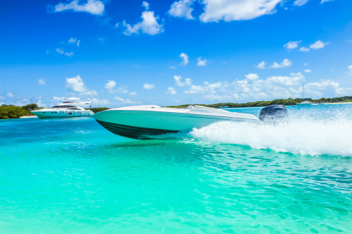 Power boat sailing at fast speed on a tropical turquoise bay. Relaxing, travel and leisure related images for vacations in the Caribbean. Image taken at Los Roques, Venezuela. Los Roques is an archipelago or group of small islands located at 80 miles north of the Venezuelan coastline and a very popular destination for leisure, diving, kite surfing and all king of water activities. Los Roques and the beauty of the turquoise coastal beaches of Venezuela are almost indistinguishable from those of the Bahamas, Fiji, Bora Bora, French Polynesia, Malau, Hawaii, Cancun, Costa Rica, Florida, Maldives, Cuba, Puerto Rico, Honduras, or other tropical areas.