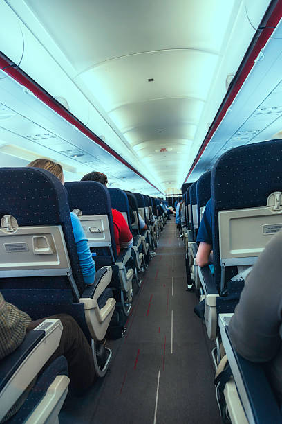 istock Airplane cabin aisle with rear view of passengers 171581896