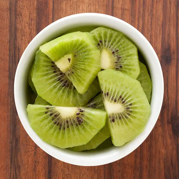 Top view of white bowl full of sliced kiwi