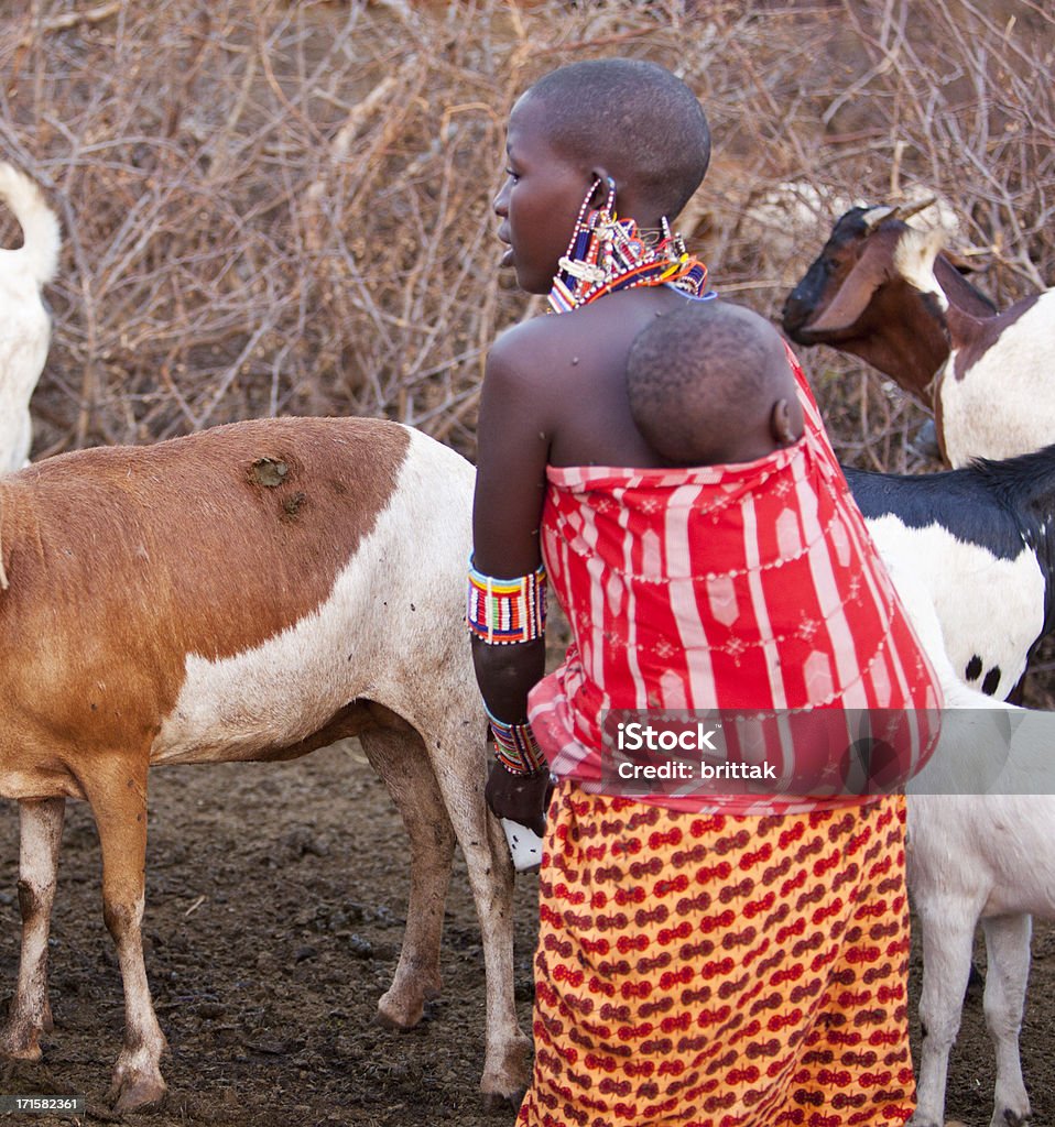 Masai madre con bambino su Indietro Mungere Capra - Foto stock royalty-free di Bebé