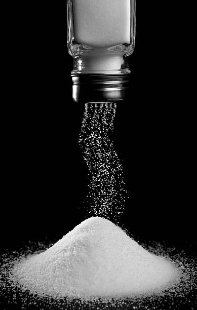 pouring salt pouring salt from salt shaker on black background sprinkling stock pictures, royalty-free photos & images